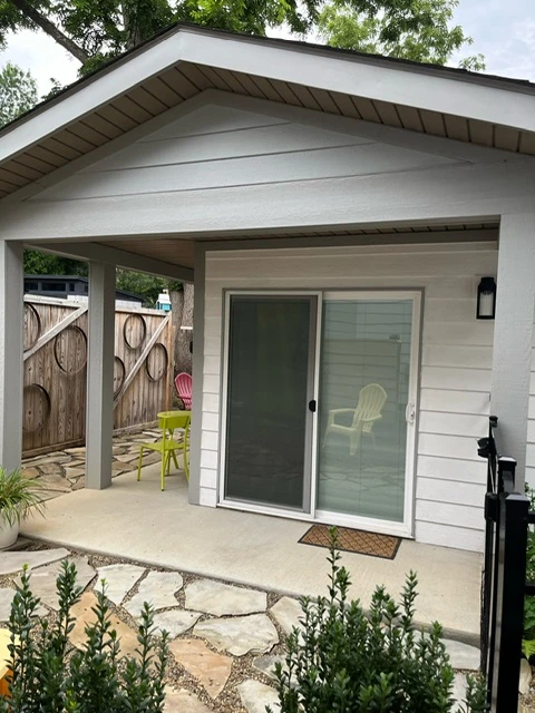 Crescent Cottage's covered entrance, sliding glass door, and stone walkway