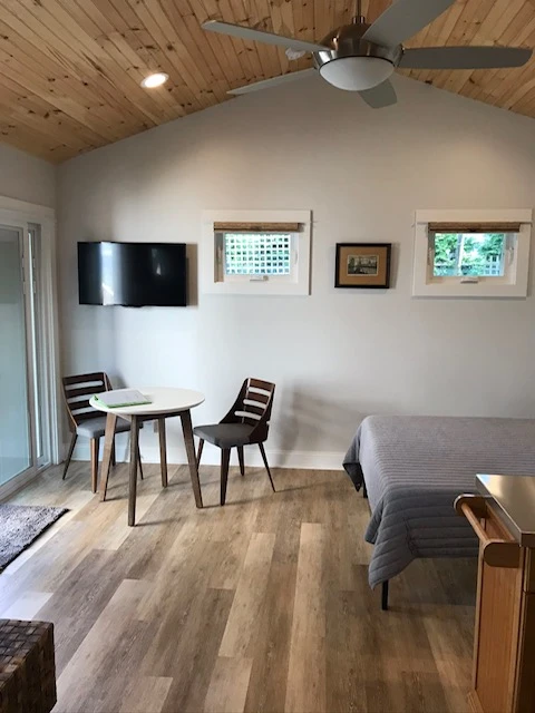 Studio interior with a wood ceiling, bed, television, and dining table